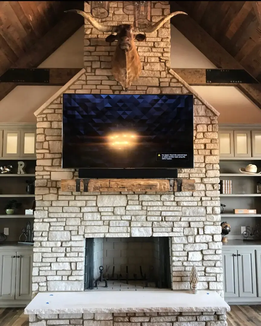 A stone fireplace with a flat screen tv mounted above it.